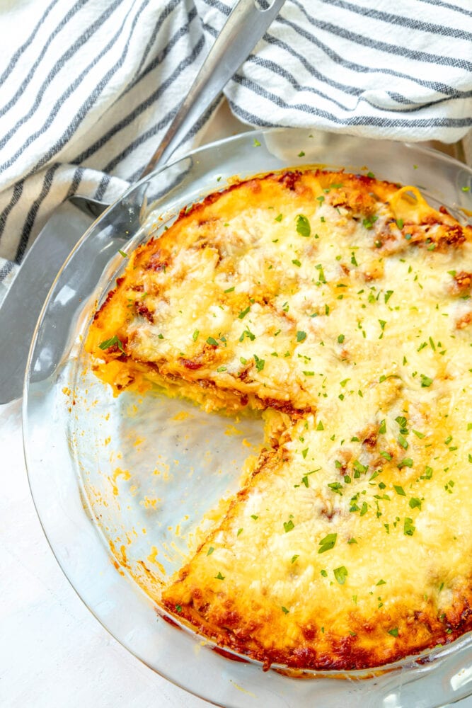 picture of baked spaghetti pie in a glass dish topped with cheese on a table