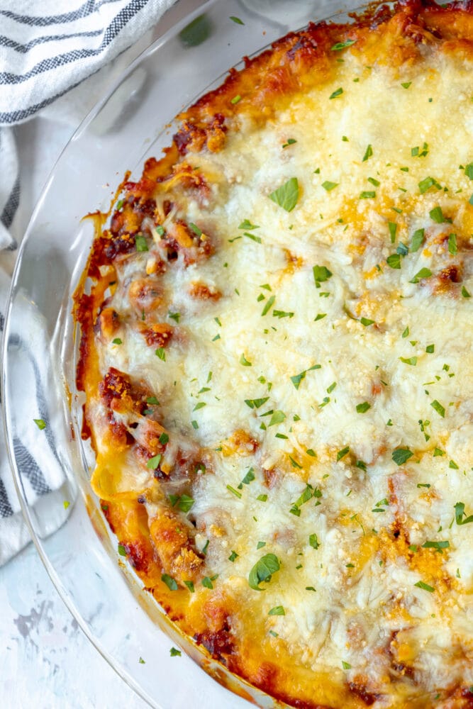 baked spaghetti pie in a glass dish topped with cheese on a table