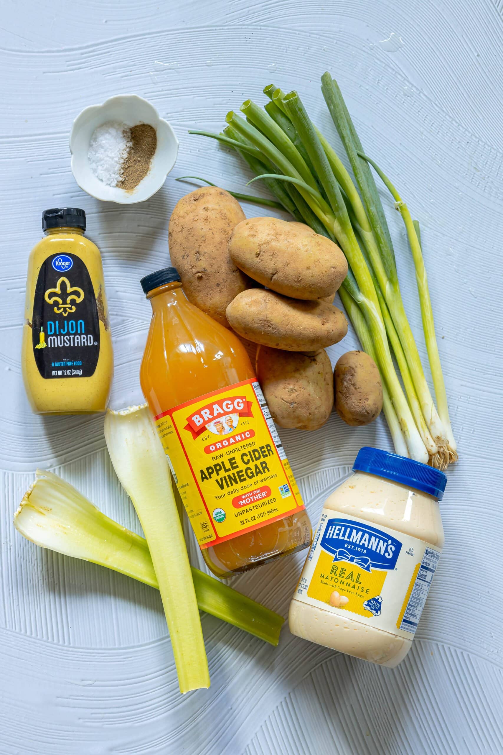 picture of celery, potatoes, mustard, salt, pepper, onions, vinegar on a table