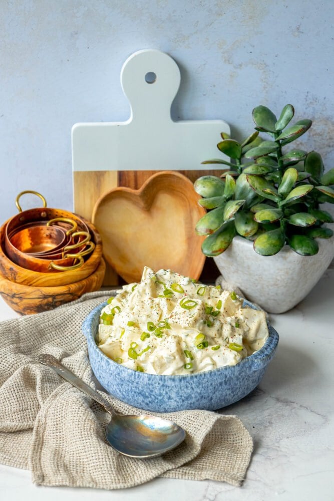 picture of creamy potato salad with green onions and cracked pepper in a blue bowl 