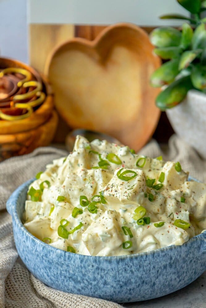 picture of creamy potato salad with green onions and cracked pepper in a blue bowl 