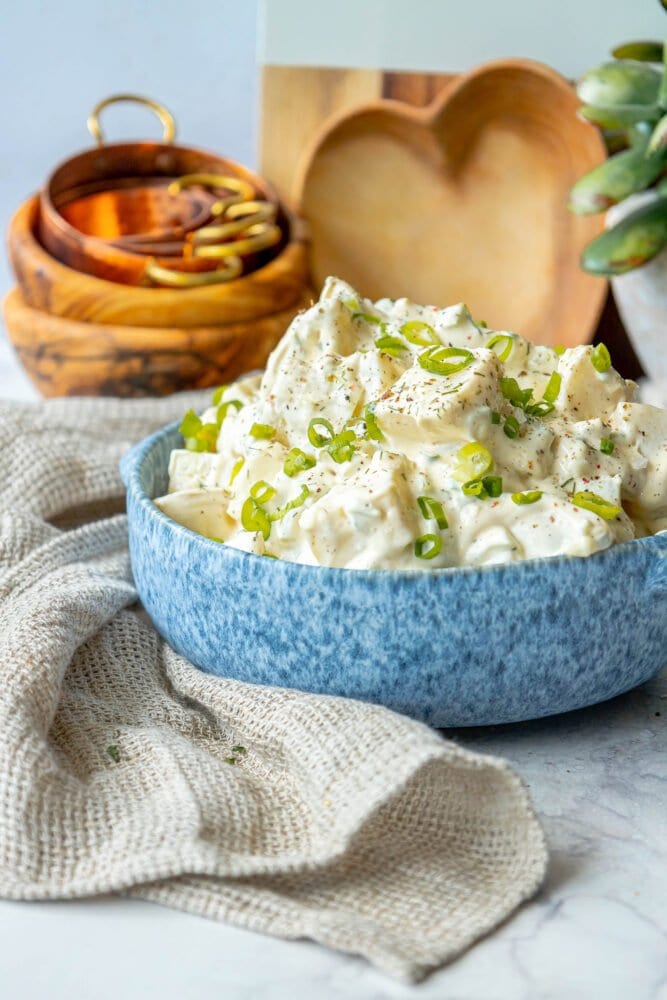 picture of creamy potato salad with green onions and cracked pepper in a blue bowl 