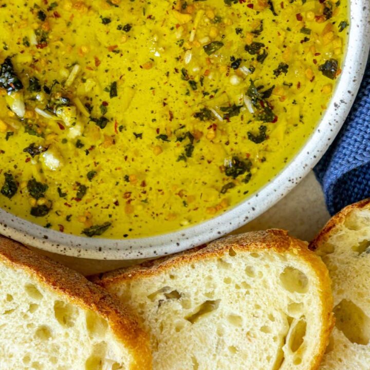picture of a slice of bread next to a bowl full of olive oil bread dip