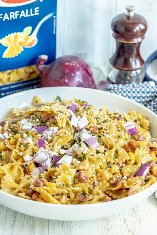 picture of tagliatelle pasta with onion, cilantro, beans, chicken thighs, and cheese in a bowl 