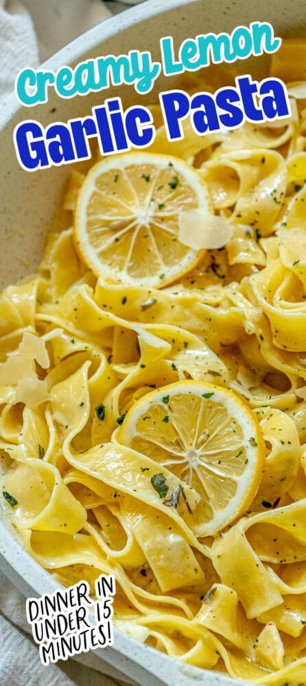 picture of papardelle pasta in a pan with sliced lemons, garlic, cream sauce, and herbs crumbled on top