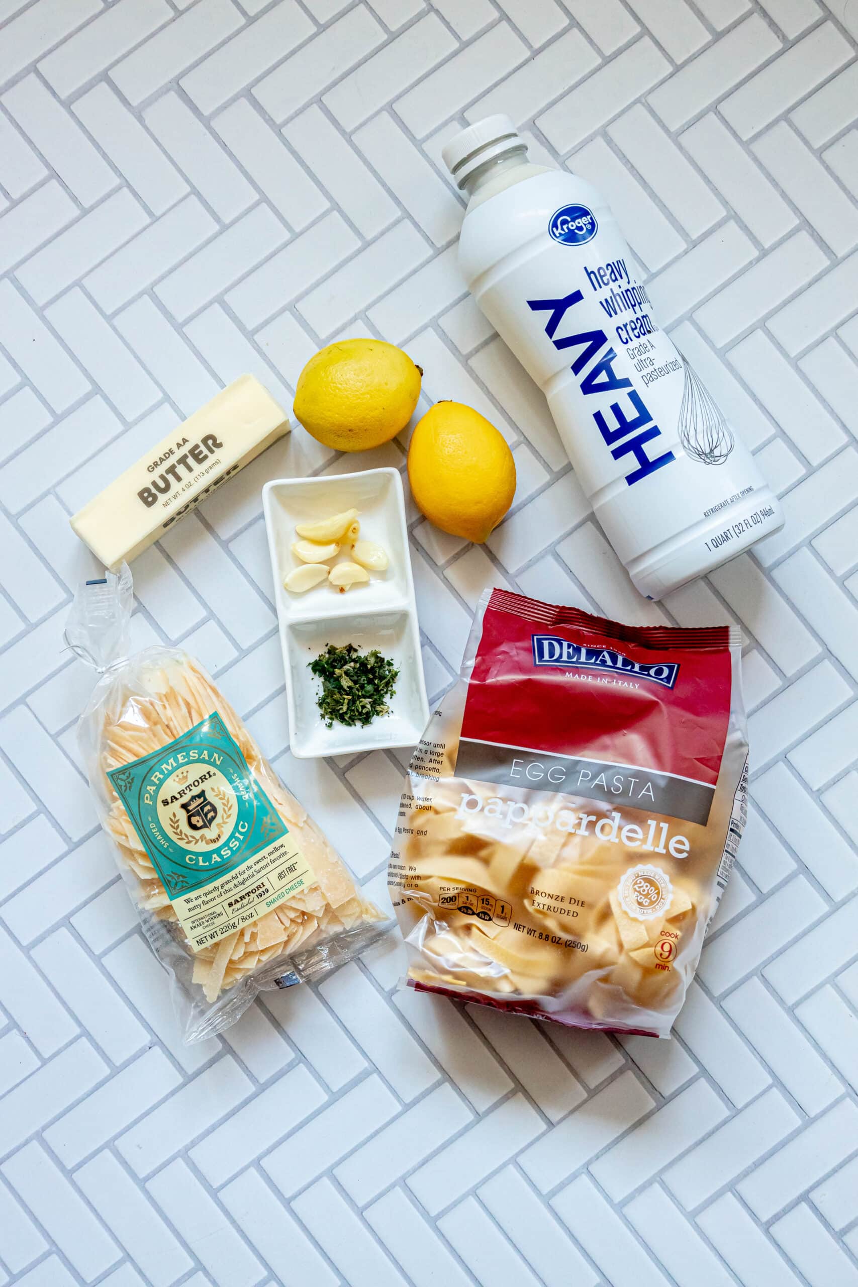 picture of cream, lemon, garlic, herbs, parmesan, butter, lemons, and pappardelle on a table