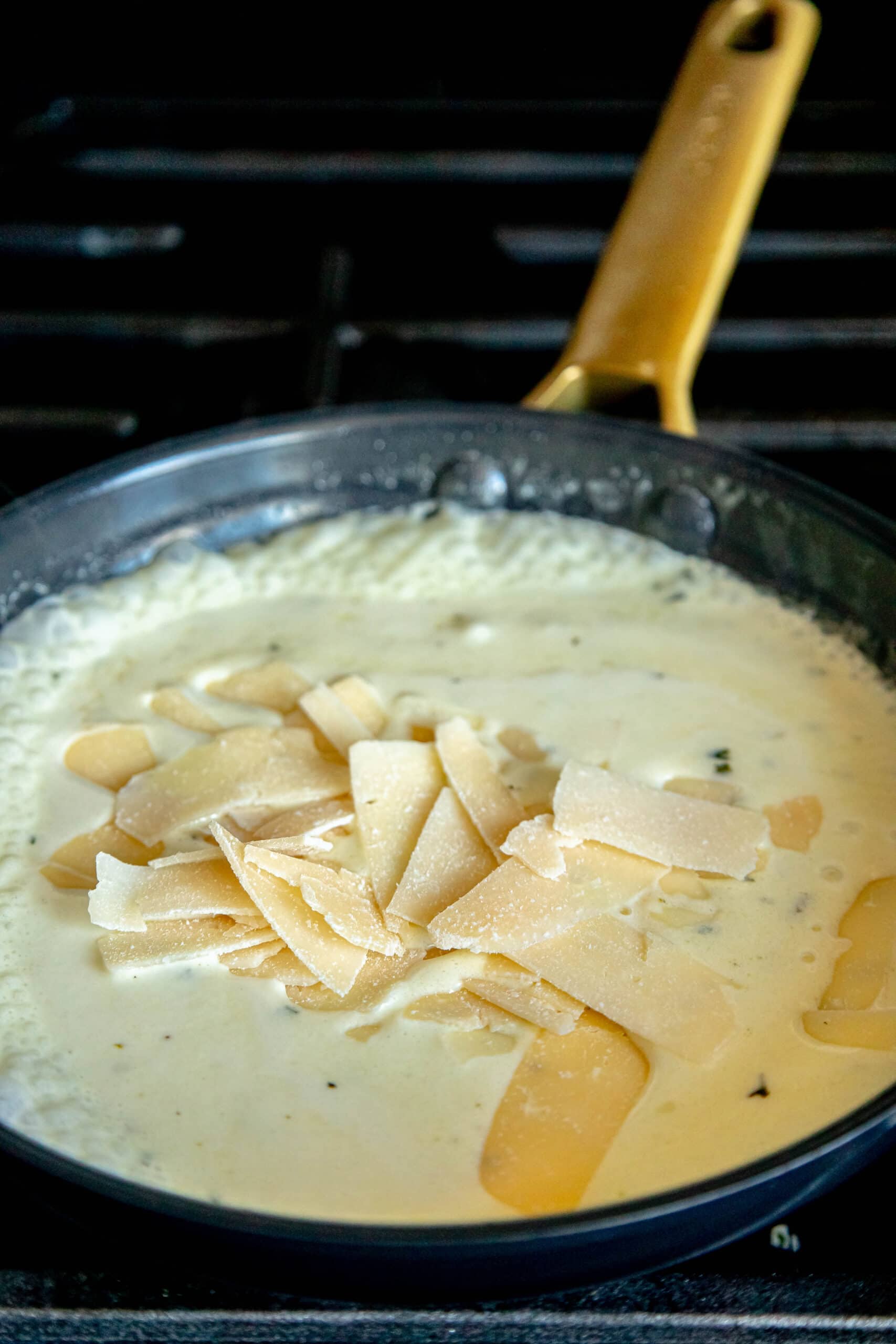 picture of creamy sauce in a pan on a stove with parmesan sprinkled over the top