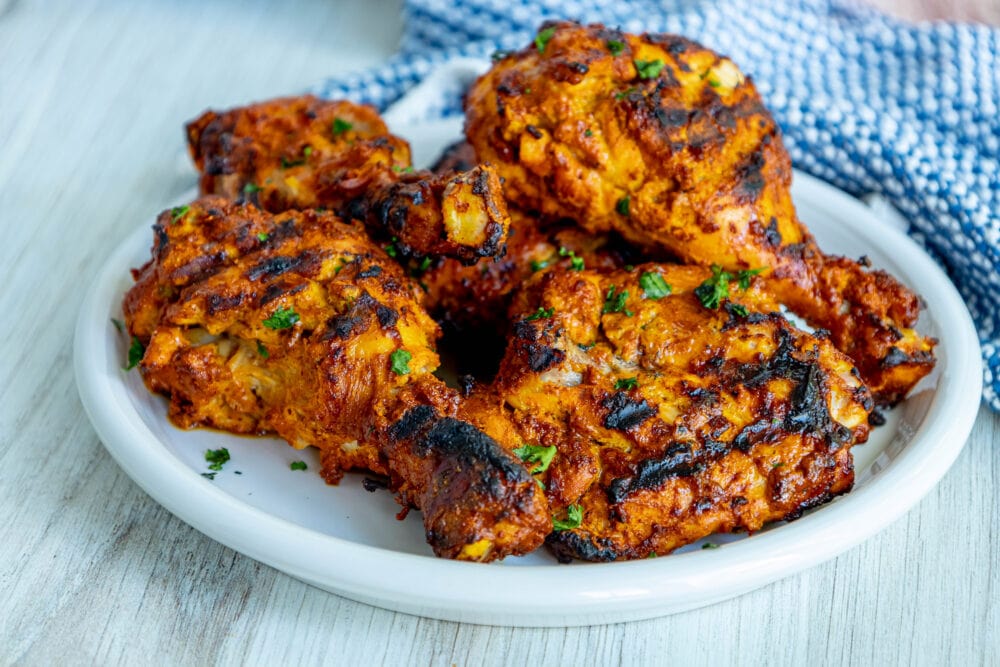 picture of grilled tandoori chicken on a plate with sliced green onions