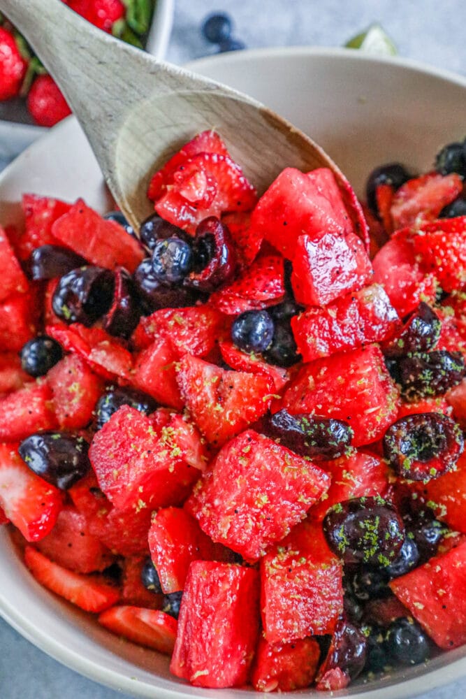 picture of sliced cherries, blueberries, strawberries, and watermelon salad with lime zest and lime honey poppyseed dressing in a bowl 