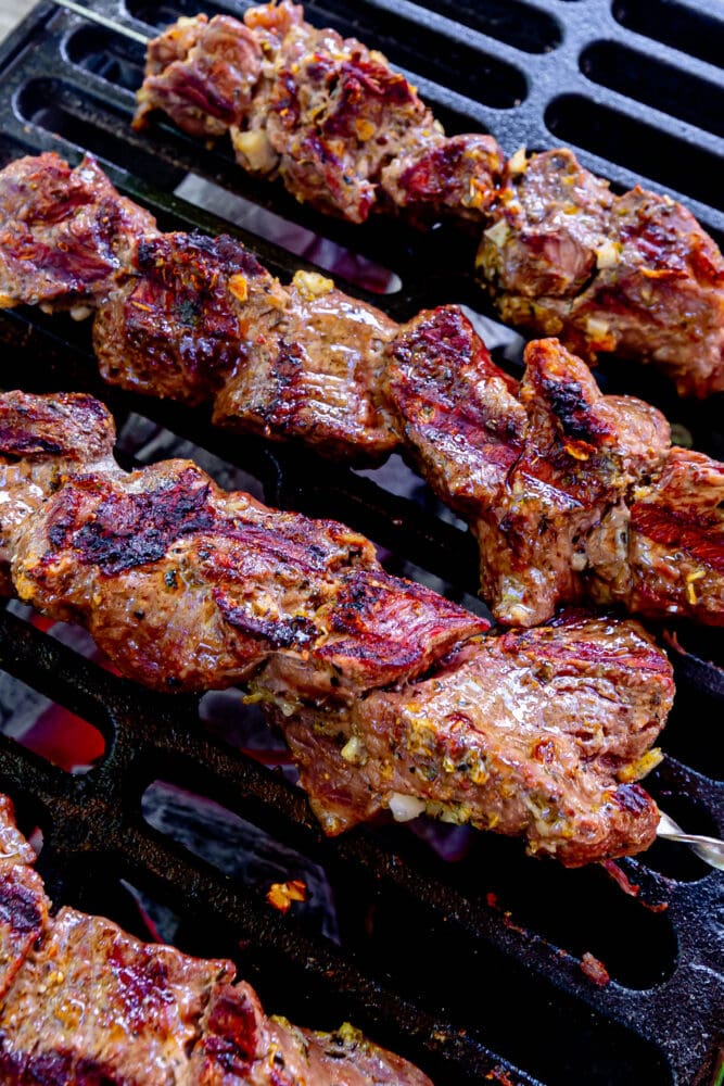 picture of lamb souvlaki on a skewer on a cast iron grill