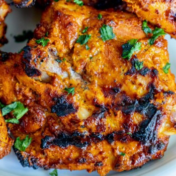 picture of grilled tandoori chicken on a plate with sliced green onions