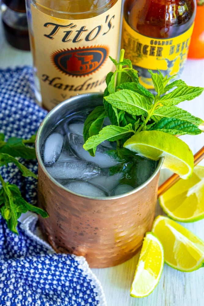 picture of moscow mule in a copper cup with mint and limes in it on a table