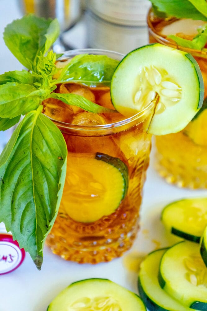 cup with cucumber and basil in it bottle of pimms in the background