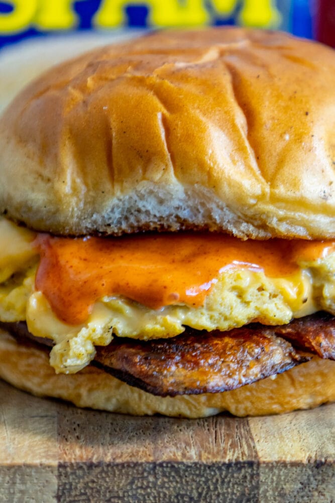 picture of fried spam and eggs on a sandwich with a spicy mayo sauce on it on a cutting board