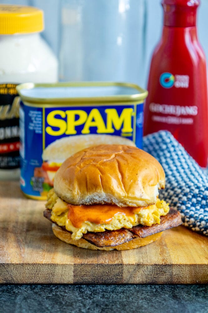 picture of fried spam and eggs on a sandwich with a spicy mayo sauce on it on a cutting board