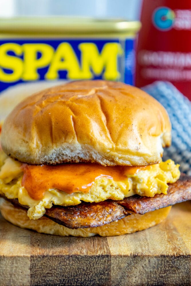 picture of fried spam and eggs on a sandwich with a spicy mayo sauce on it on a cutting board