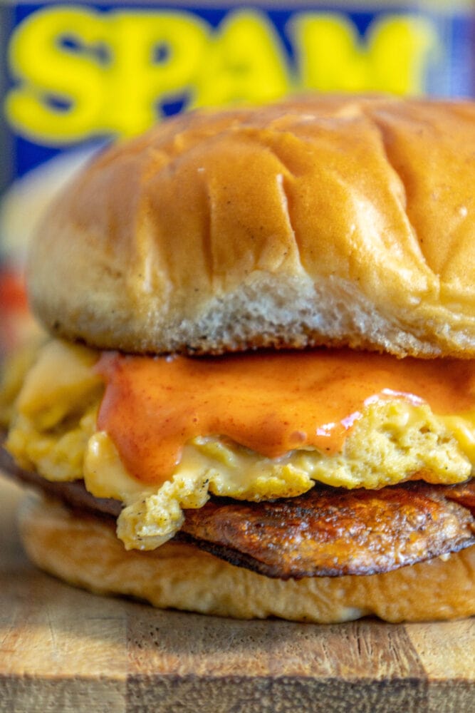 picture of fried spam and eggs on a sandwich with a spicy mayo sauce on it on a cutting board