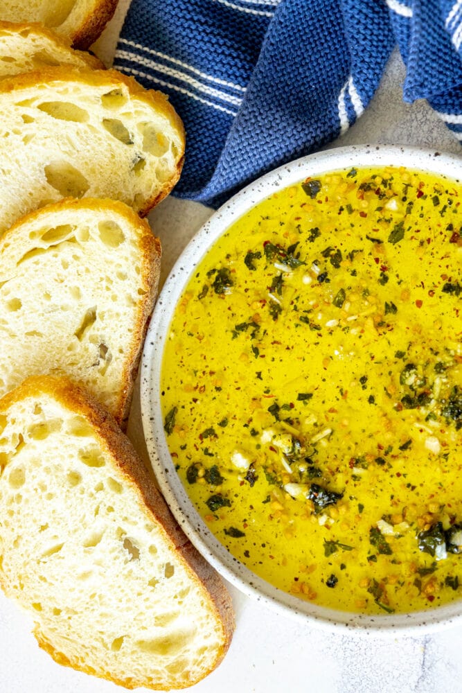 picture of a slice of bread next to a bowl full of olive oil bread dip 