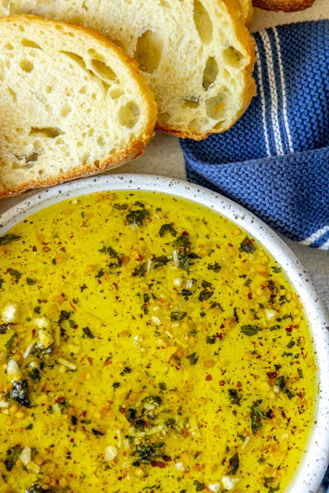 picture of a slice of bread next to a bowl full of olive oil bread dip 