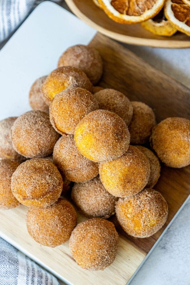 picture of donut holes rubbed in cinnamon sugar stacked on a cutting board