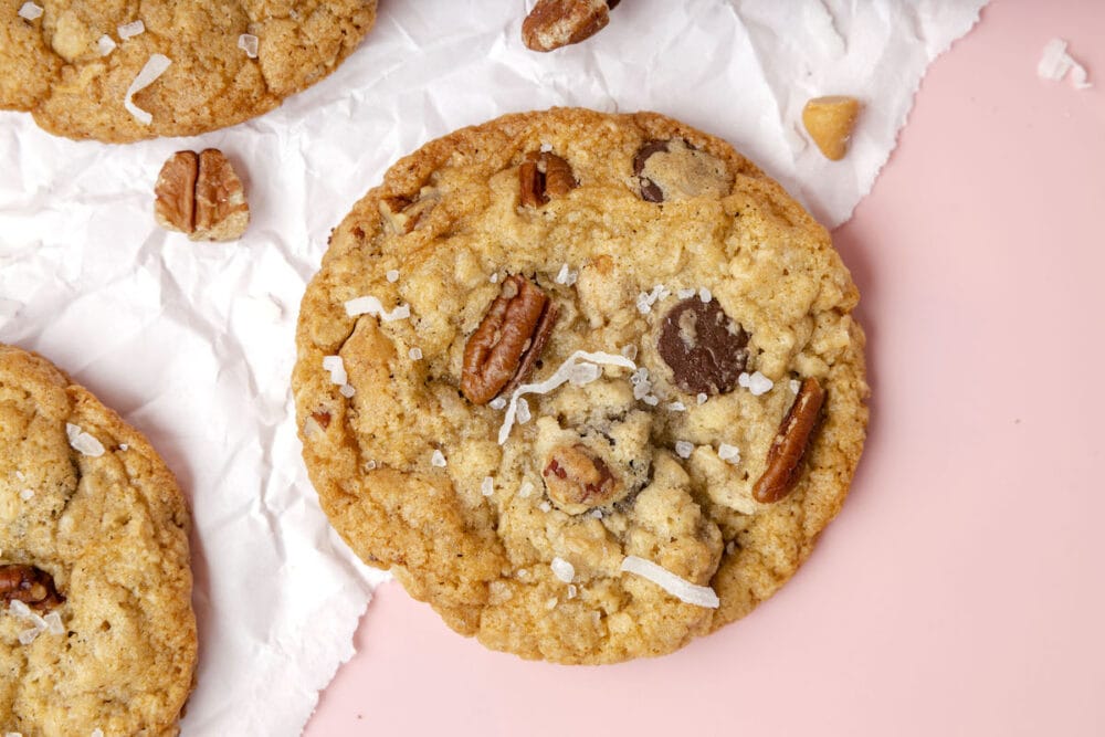 picture of a chocolate chip and oatmeal cookie with butterscotch chips, pecans, coconuts, and salt on top