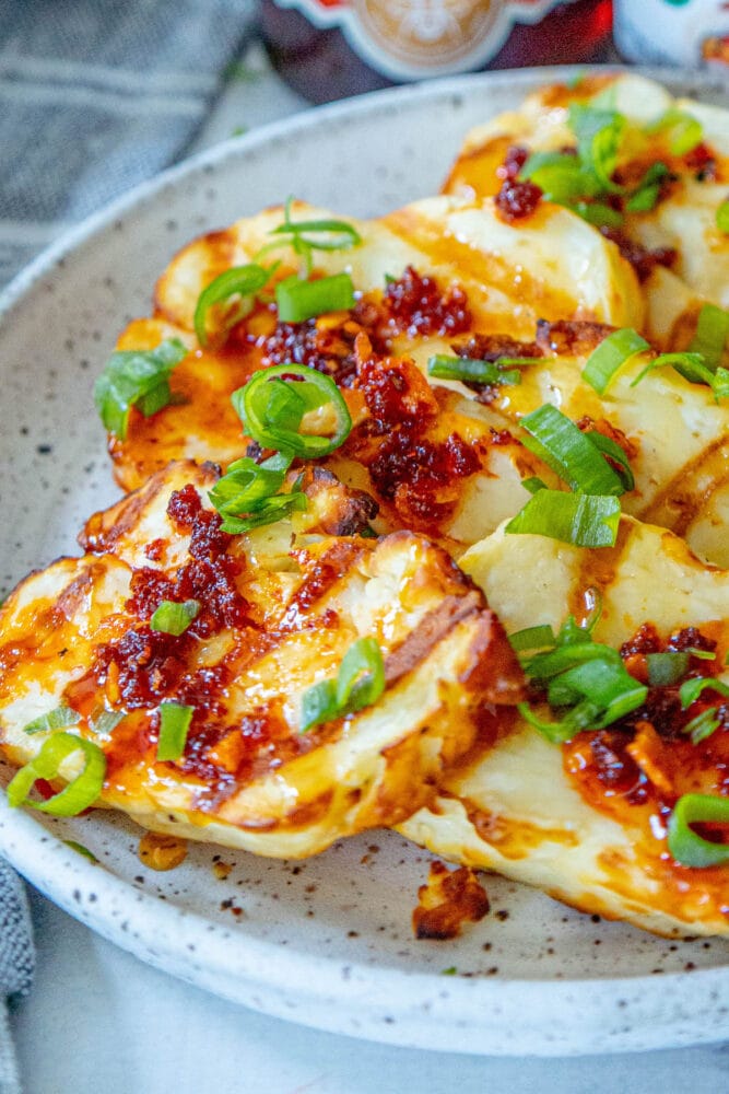 picture of grilled halloumi on a plate topped with spicy garlic, scallions, and honey