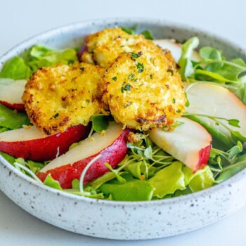 picture of butter lettuce salad with sliced pears and goat cheese balls with champagne vinaigrette dressing on top