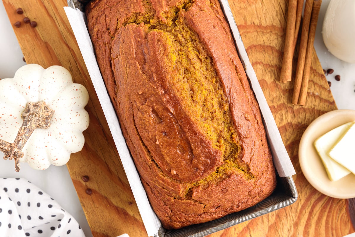 picture of pumpkin bread in a loaf pan on a cutting board