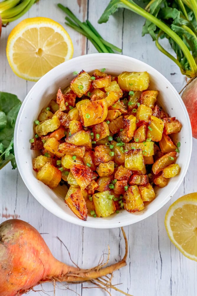 picture of golden roasted beets in a white bowl with chopped chives on top