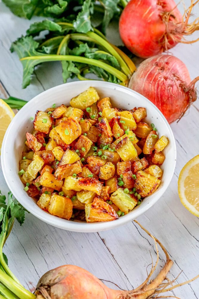 picture of golden roasted beets in a white bowl with chopped chives on top