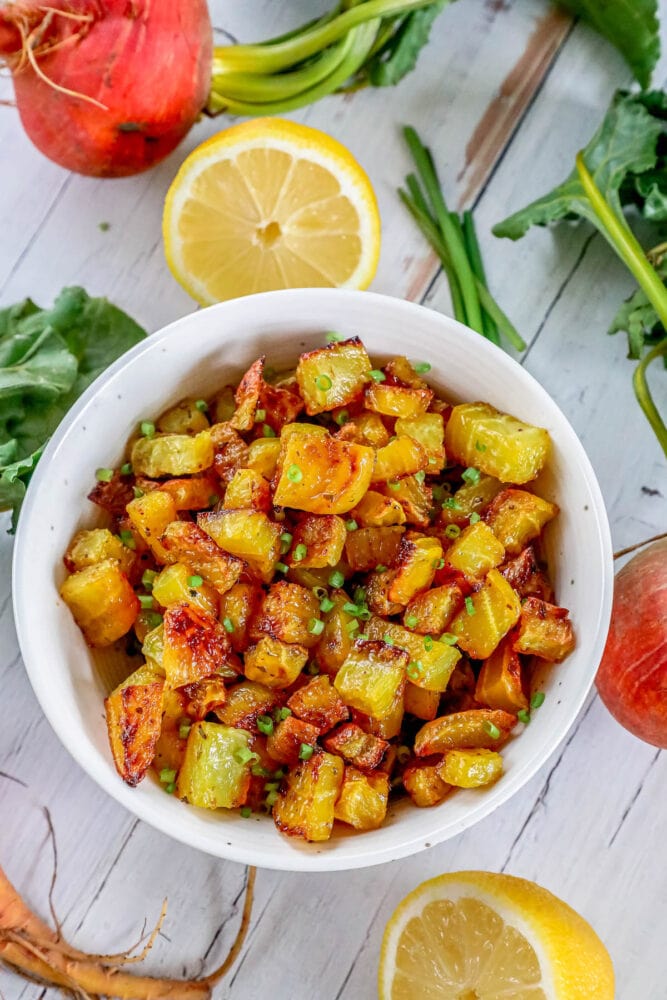 picture of golden roasted beets in a white bowl with chopped chives on top