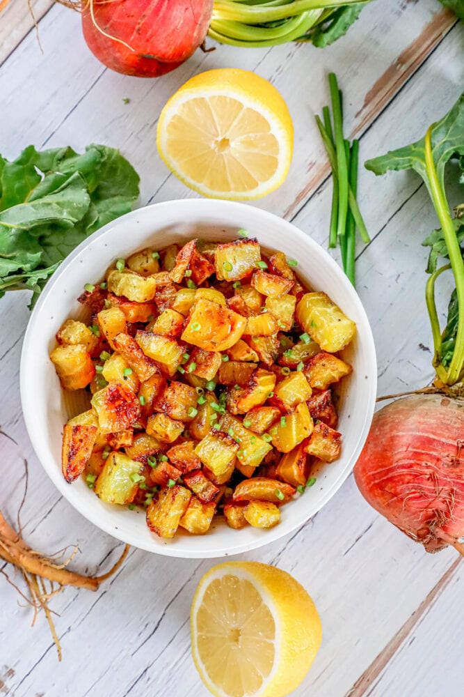 picture of golden roasted beets in a white bowl with chopped chives on top