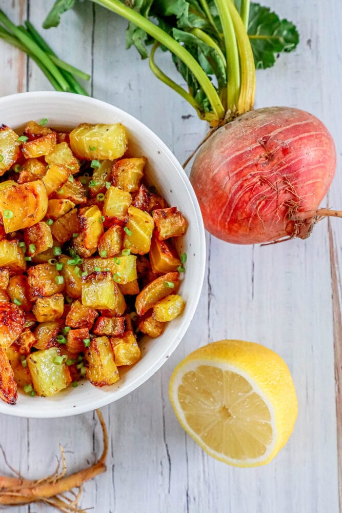 picture of golden roasted beets in a white bowl with chopped chives on top