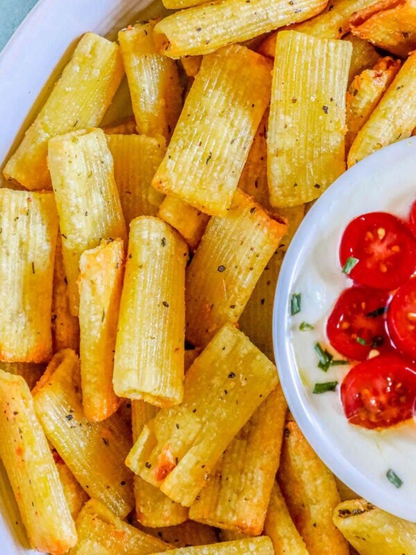 picture of air fried pasta chips in a bowl with feta dip with tomatoes sliced on top