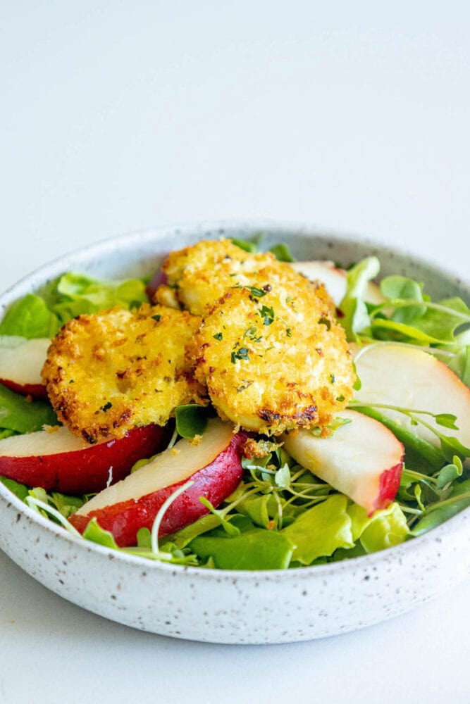 picture of butter lettuce salad with sliced pears and goat cheese balls with champagne vinaigrette dressing on top 