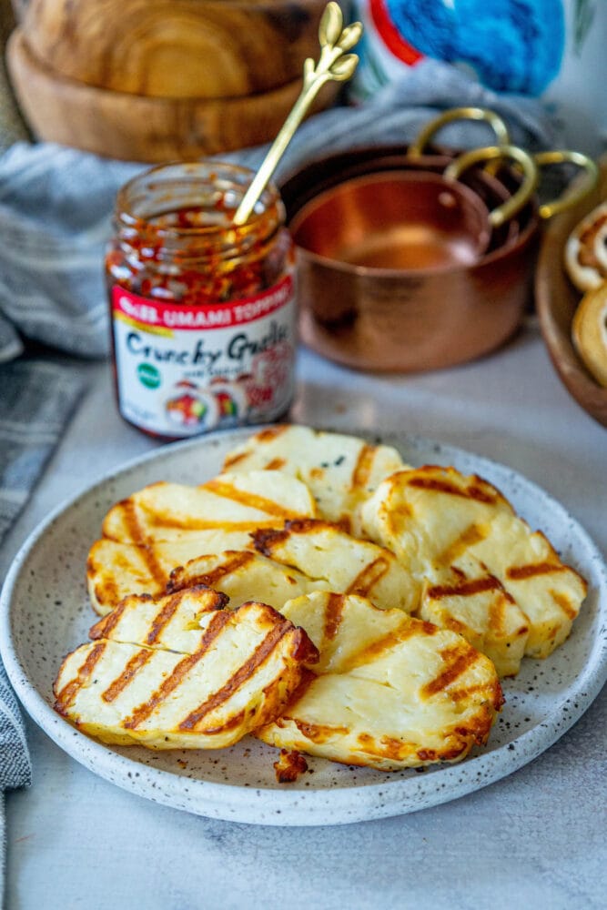 picture of grilled halloumi on a plate in front of spicy garlic and honey