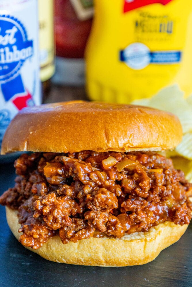 picture of sloppy joe in a bun with lots of sauce on a table