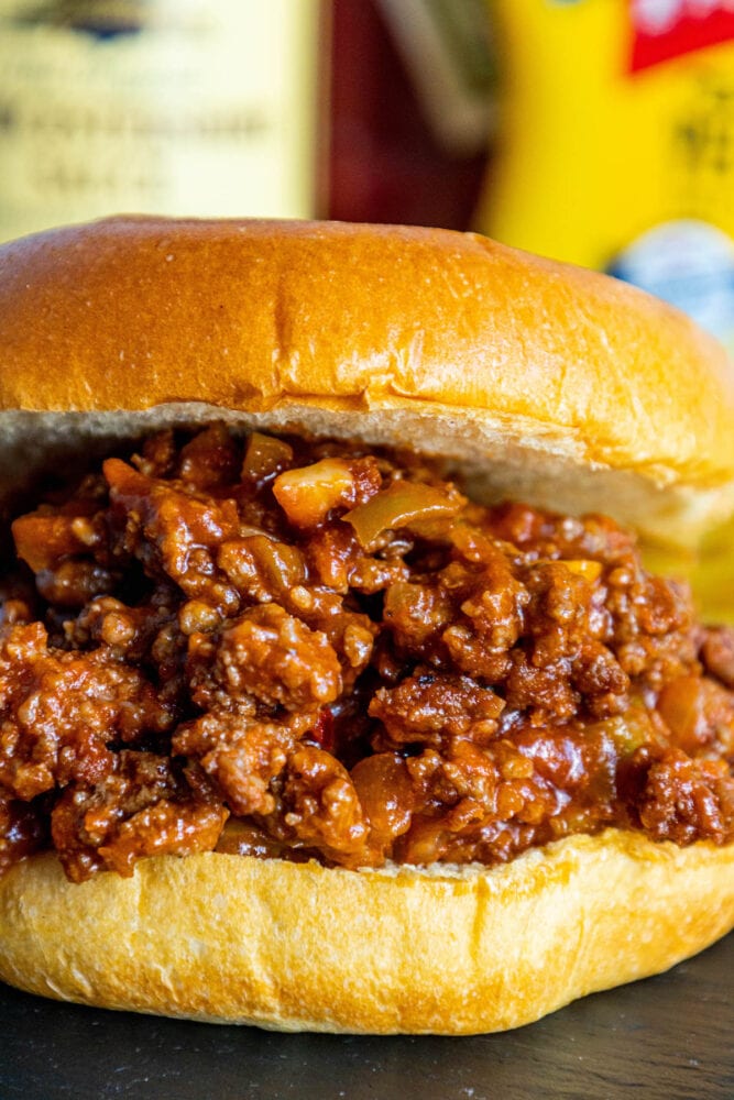 sloppy joe sandwich in a bun with lots of sauce on a table