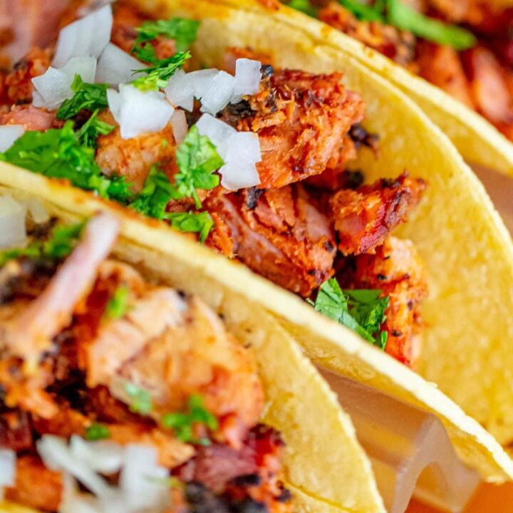 picture of chopped smoked al pastor in a taco topped with onions and diced cilantro