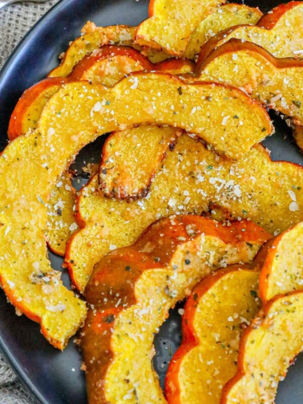 picture of roasted acorn squash seasoned with herbs and spices on a black plate