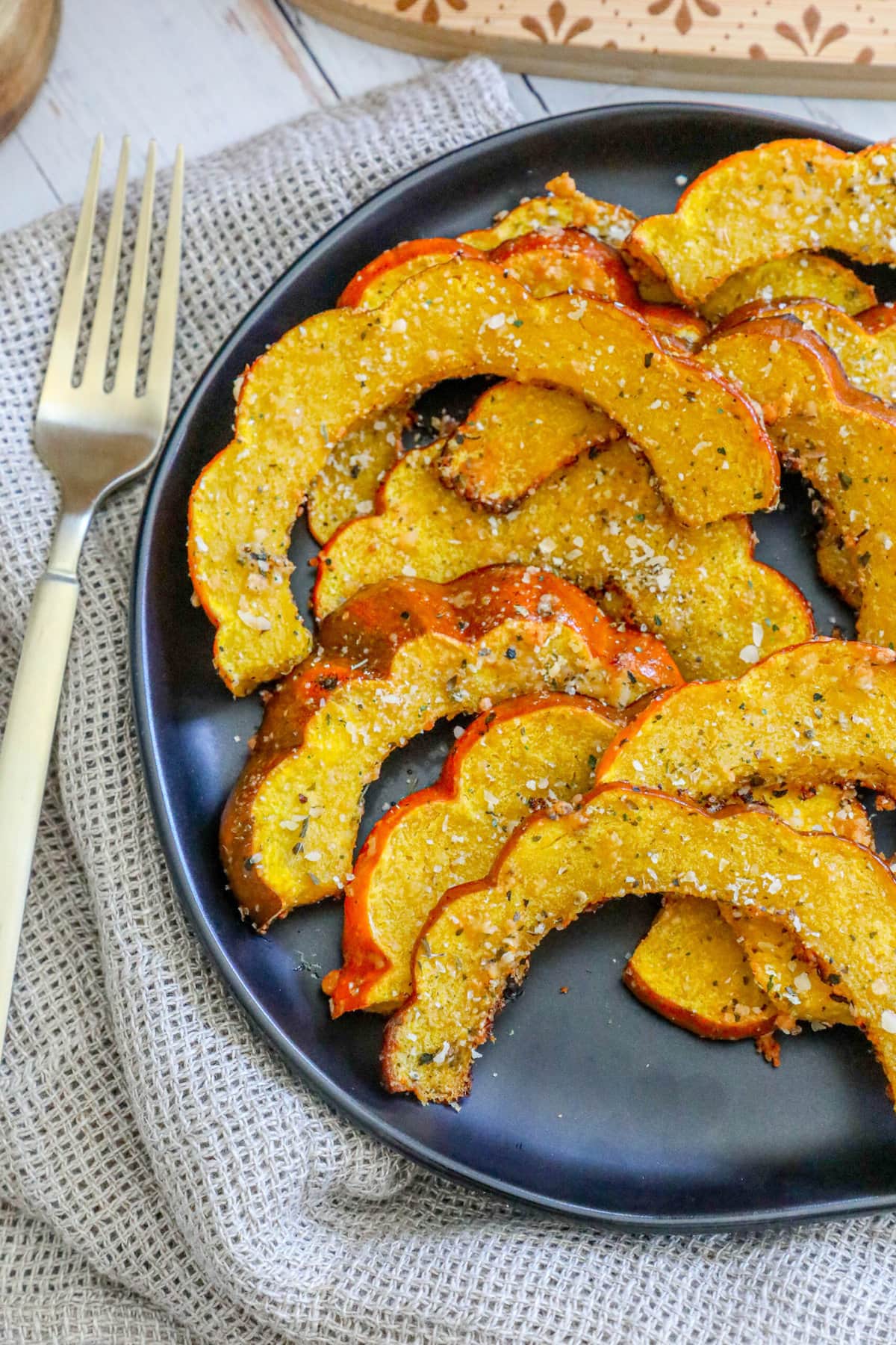 picture of roasted acorn squash slices seasoned with herbs and spices on a black plate