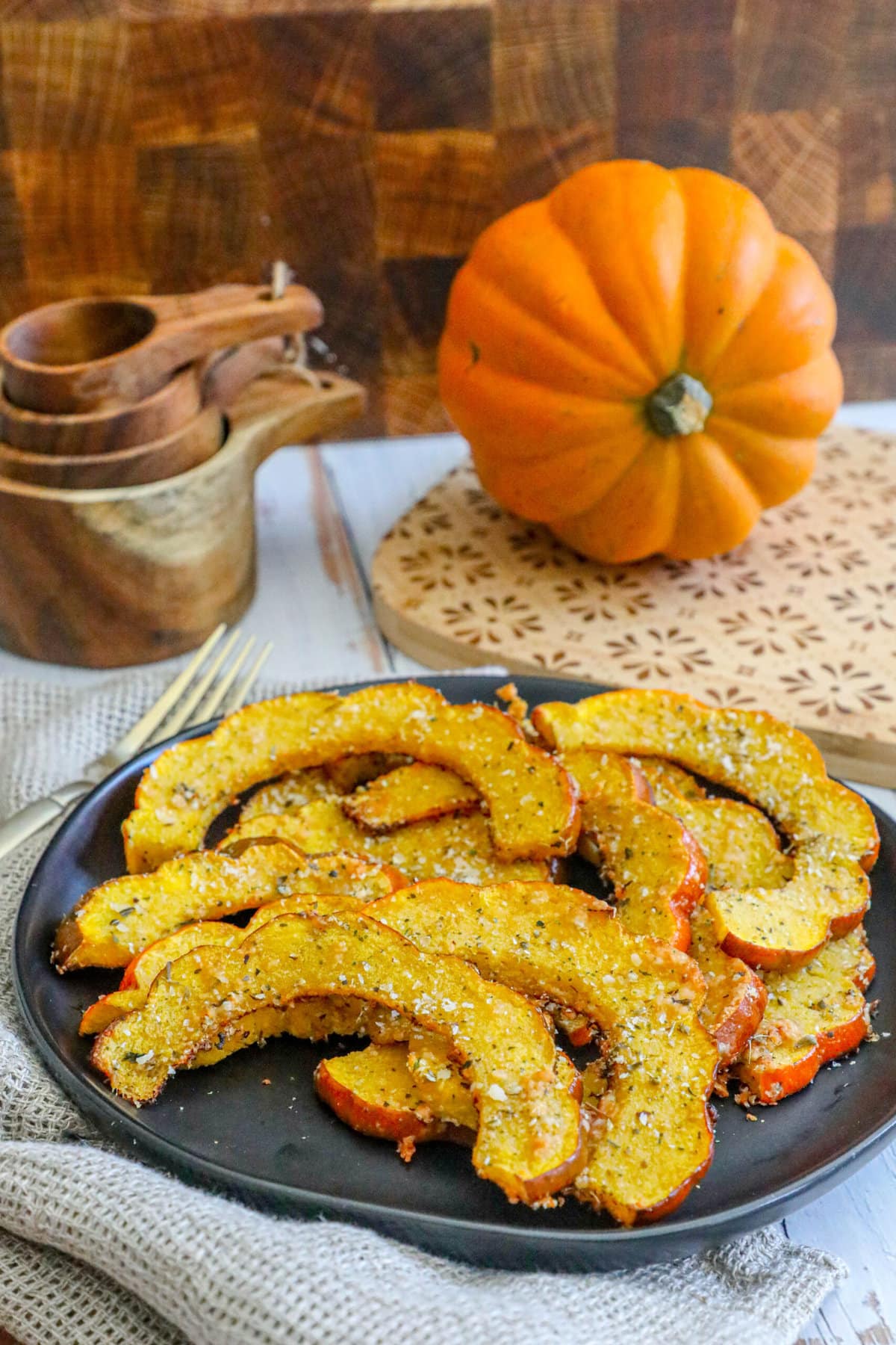 picture of roasted acorn squash slices seasoned with herbs and spices on a black plate