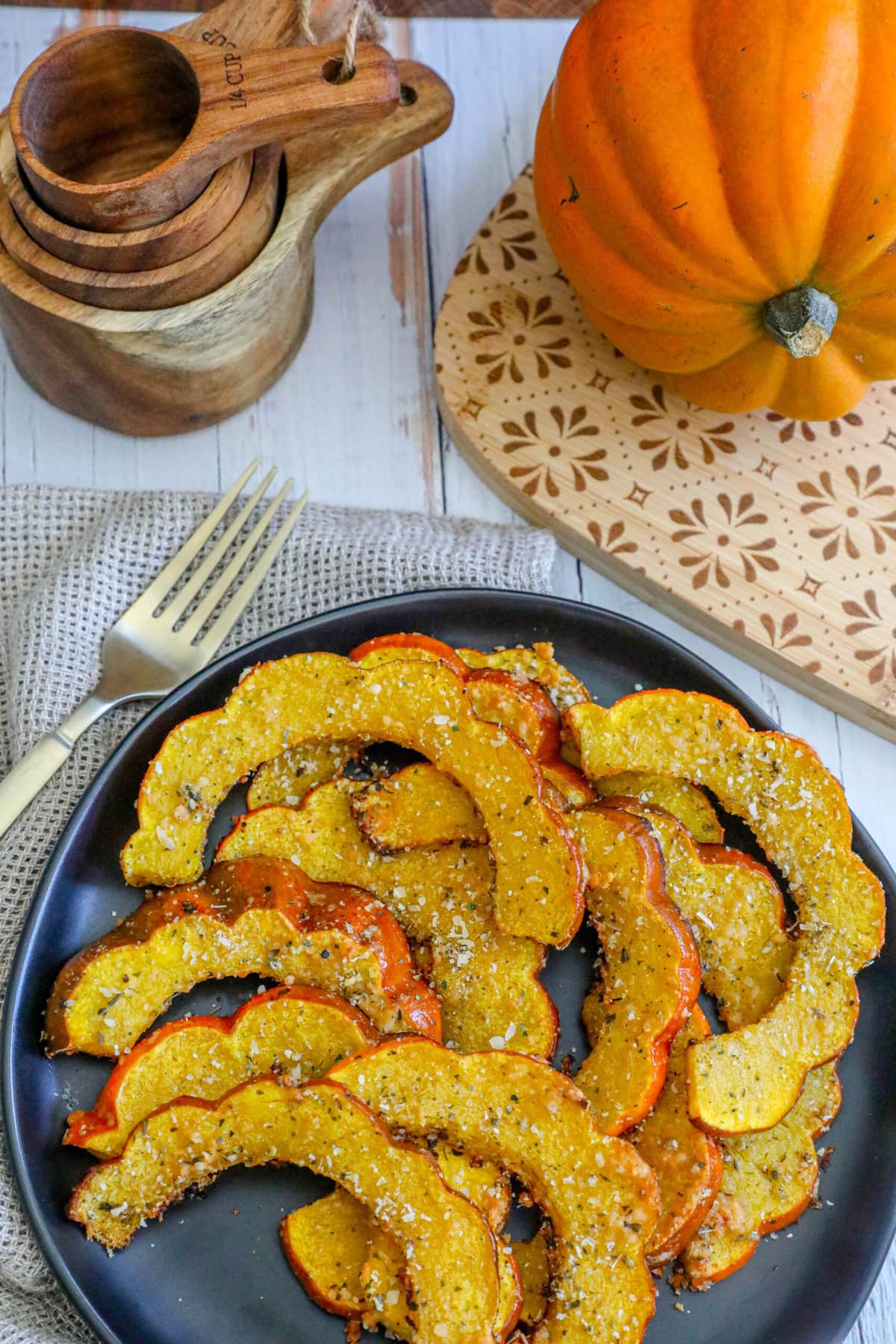 picture of roasted acorn squash slices seasoned with herbs and spices on a black plate