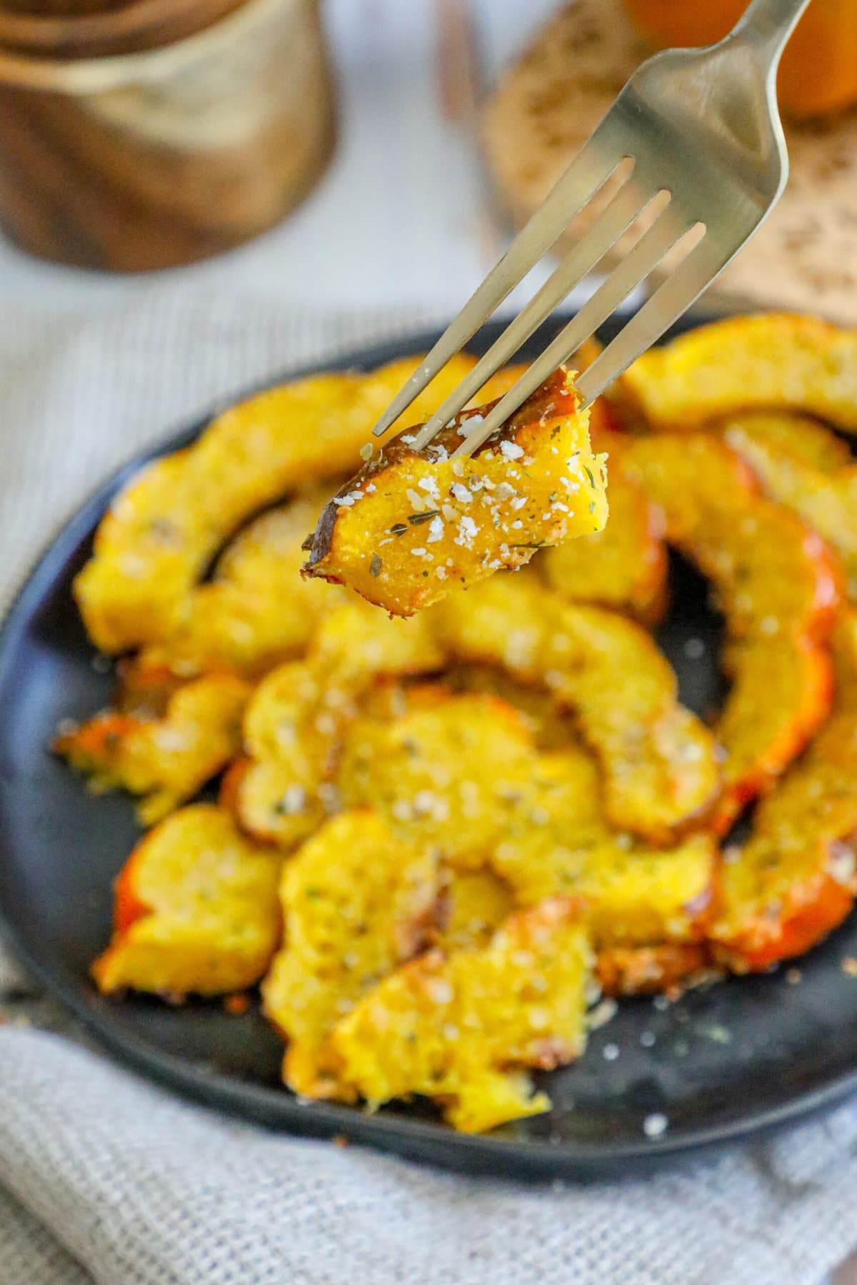 picture of roasted acorn squash slices seasoned with herbs and spices on a black plate