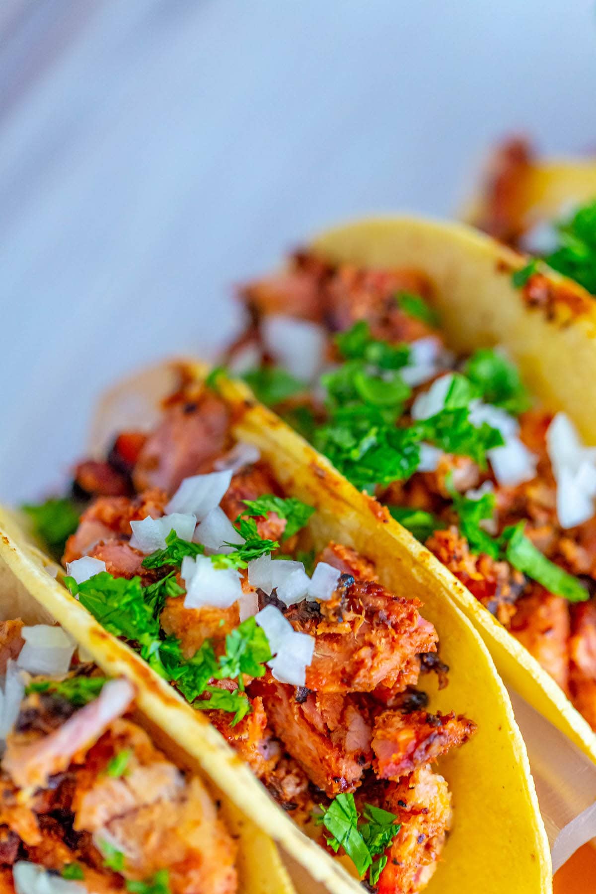 picture of chopped smoked al pastor in a taco topped with chopped cilantro and white onion