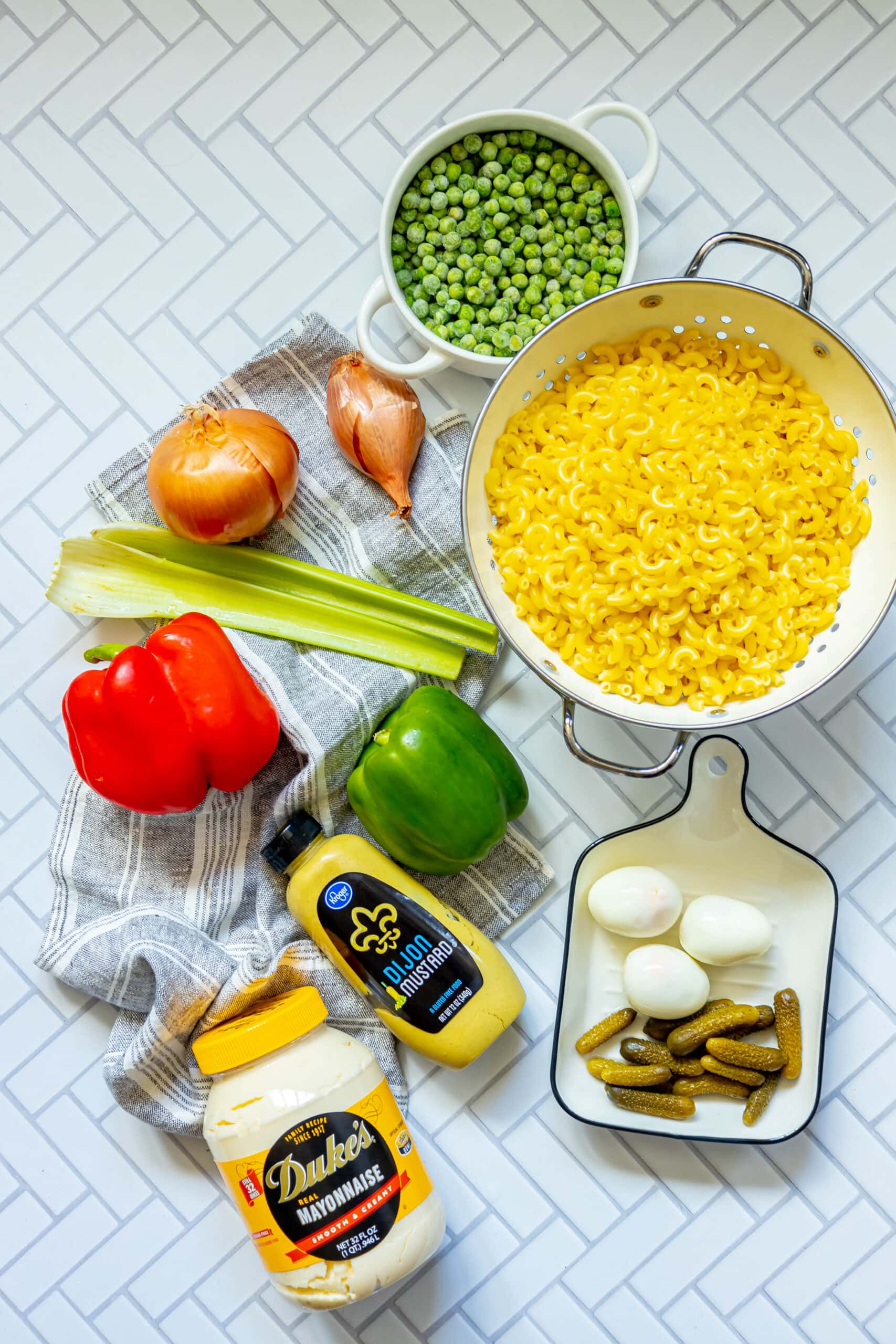 picture of macaroni, shallots, celery, peppers, peas, boiled eggs, gherkins, mustard, mayonnaise, herbs and spices on a table