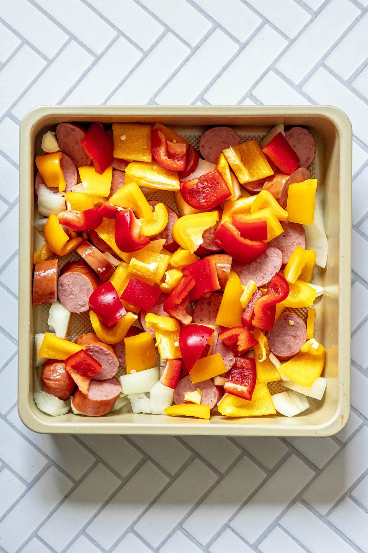 picture of sliced turkey kielbasa, onions, and bell peppers in a pan