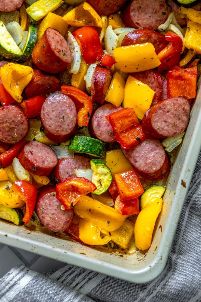 picture of turkey kielbasa, bell peppers, onions, and herb dressing baked on a baking sheet on a table