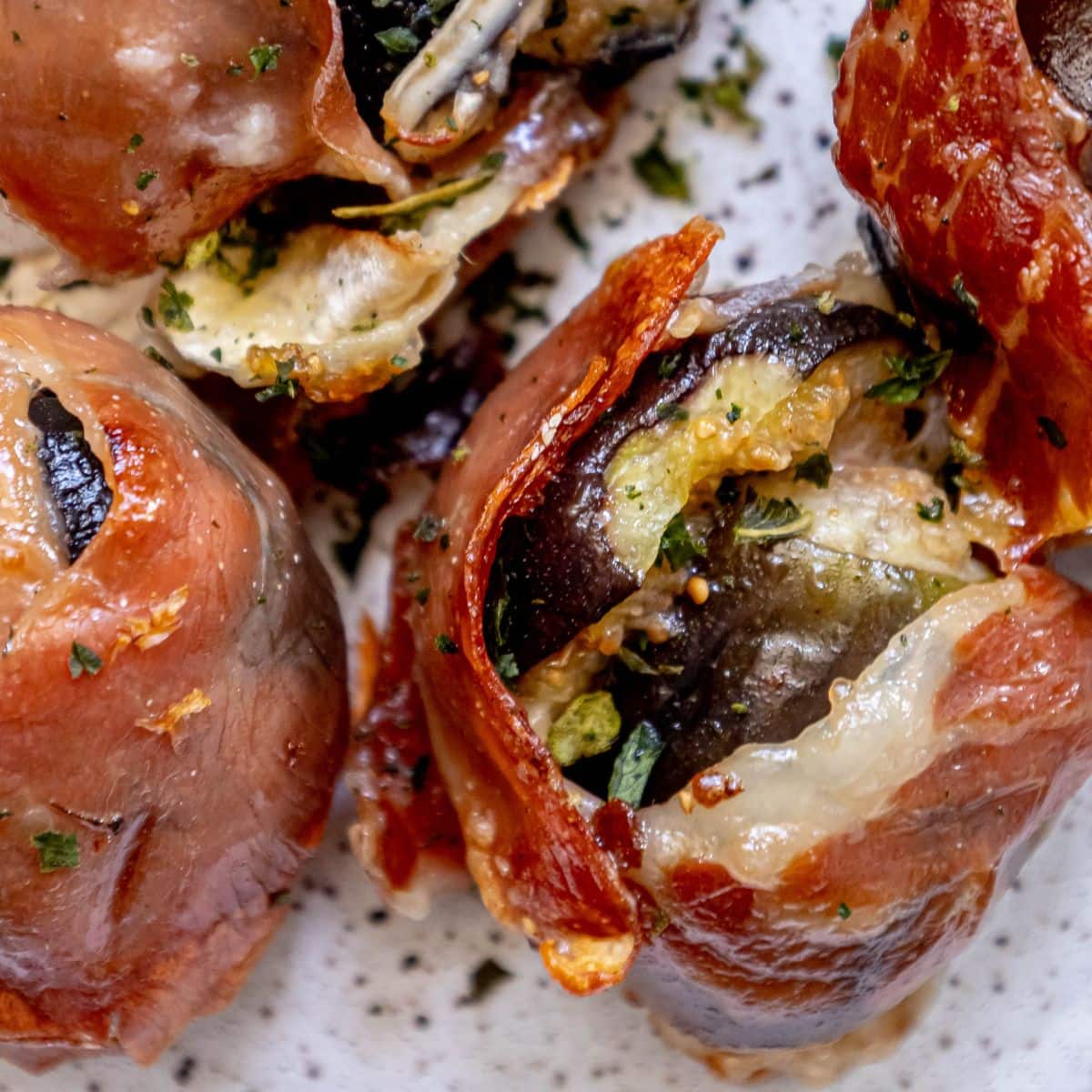 picture of fig stuffed with brie and wrapped in prosciutto on a plate with chives