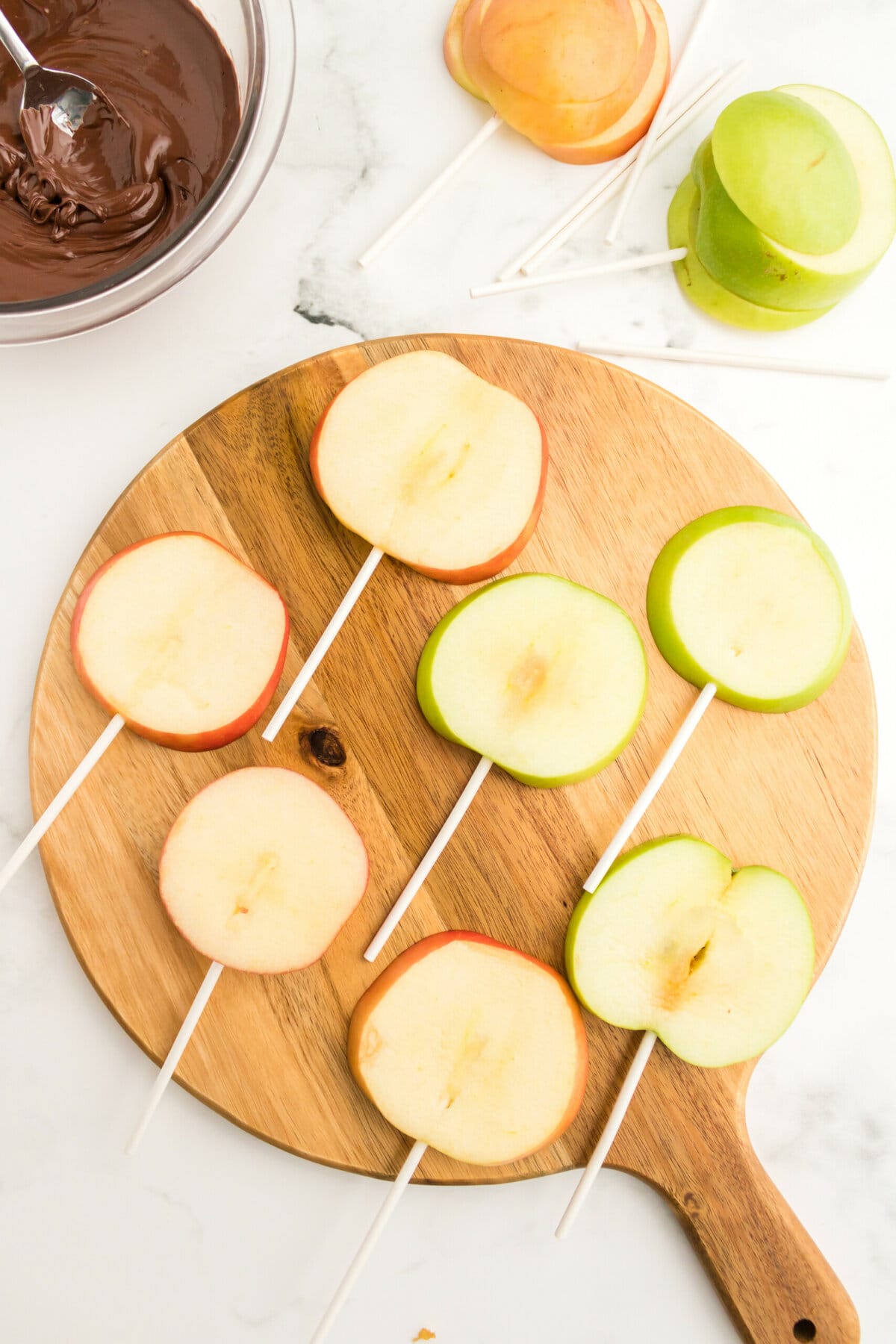 picture of sliced apples on a cutting board with sticks in them